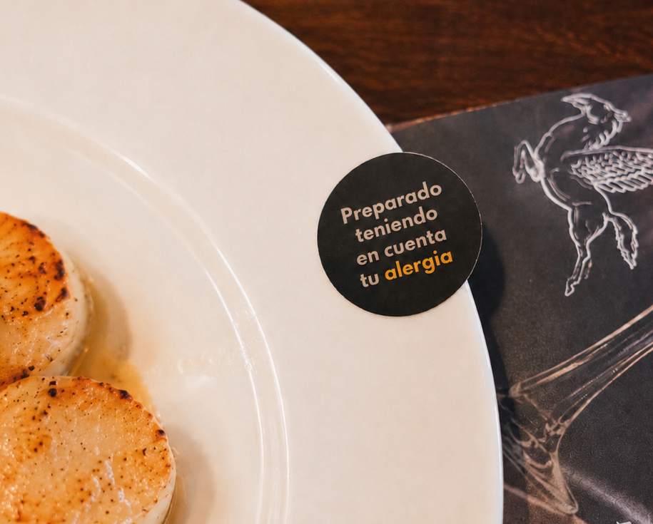Plato de vieiras con la pegatina Comensalios «Preparado teniendo en cuenta tu alergia» en el borde